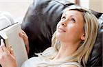 Charming woman reading a book lying on a sofa at home