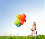 Adorable young girl holds tightly to a large bunch of helium filled balloons