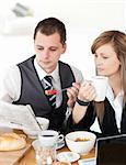 Young couple of business people reading a newspaper while having breakfast at home