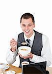 Smiling businessman eating cereals looking at the camera against white background