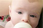 Baby blond little girl feeding drinking milk in a bottle