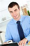 Handsome businessman using a laptop in the kitchen at home