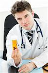 Beautiful doctor holding pills in his office