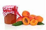Apricot jam with fruit whole and in half with leaf sprigs, isolated over white background.