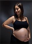 Pregnant woman holding her belly over a gray background.