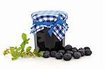 Blueberry jam and flower leaf sprig with loose blueberries, isolated over white background.