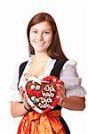 Woman in love dressed with Oktoberfest dirndl holding gingerbread heart. Isolated on white background.