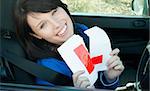 Cheerful young female driver tearing up her L sign sitting in her car