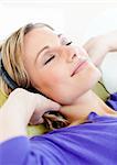 Relaxed woman listen to music lying on a sofa at home
