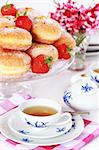 Doughnut filled with strawberry jam - German national dish with cup of tea