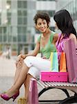 two women relaxing on bench after shopping. Vertical shape, full length, copy space