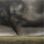 A large tornado working its way across fields.