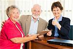 Financial consultant gives thumbs up as she advises retired couple.
