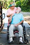 Disabled senior man in wheelchair with his loving wife taking care of him.