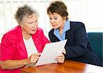 Senior woman and her broker or consultant going over paperwork together.