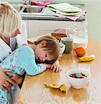 Young mother and daughter having breakfast in kitchen