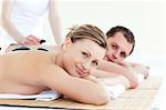 Smiling young couple having a stone massage in a spa center