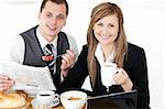 Joyful couple of businesspeople having breakfast smiling at the camera against white background