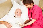 Friendly home caregiver reads to an elderly patient.