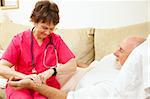 Home health nurse taking the pulse of an elderly, home-bound patient.