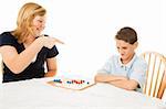 Teen girl makes fun of her little brother during a board game.  White background.