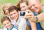 Happy family of five smiling at camera as grandfather clicks moment of the day