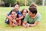 Playful family lying outdoors and smiling at camera during a sunny day