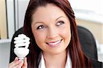 Delighted businesswoman holding a light bulb in her office