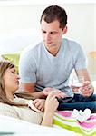 Caring man giving his sick girlfriend pills and water in the living room
