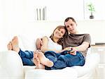 Affectionate couple lying on the sofa watching television in the living room