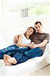 Loving couple lying on the sofa smiling at the camera in the living room