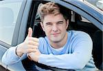 Attractive young man sitting in his car with thumb up smiling at the camera