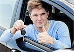 Charming young man holding a car sitting in his car smiling at the camera