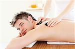 Charming young man receiving a back massage with hot stone in a spa center