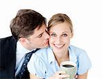 Attentive businessman kissing his girlfriend at her cheek against white background