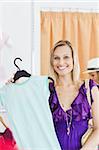 Happy blond woman looking at a shirt in a clothes store doing shopping