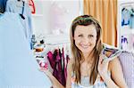 Close-up of a smiling woman doing shopping looking at the camera in a clothes store