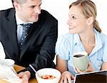 Affectionate young couple having breakfast using their laptop at home