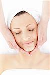 Pretty young woman enjoying a facial massage in a spa center