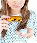 Close up of female patient taking pills against white background