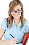 bright woman writing on a folder sitting in her desk smiling at the camera