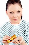 Dejected ill woman holding pills looking at the camera against white background