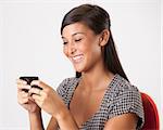 Beautiful young Asian woman smiles while writing a text message on her mobile phone. Horizontal shot.