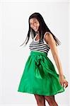 Beautiful young Asian woman models a green skirt. She is smiling towards the camera and has her hair in motion. Vertical shot.