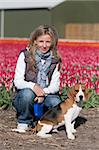 Young woman walking with her beagle dog on flower fields