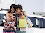 two women standing by limousine and taking picture on mobile phone. Horizontal shape, waist up, copy space