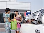 two women standing by limousine and looking at shopping bags. Horizontal shape, copy space