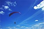 Paragliding on a sunny day with various clouds in the blue sky.