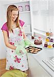 Cute young woman baking cookies in the kitchen at home
