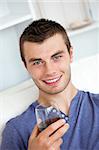 Animated young man drinking wine looking at the camera sitting on the sofa in the living-room